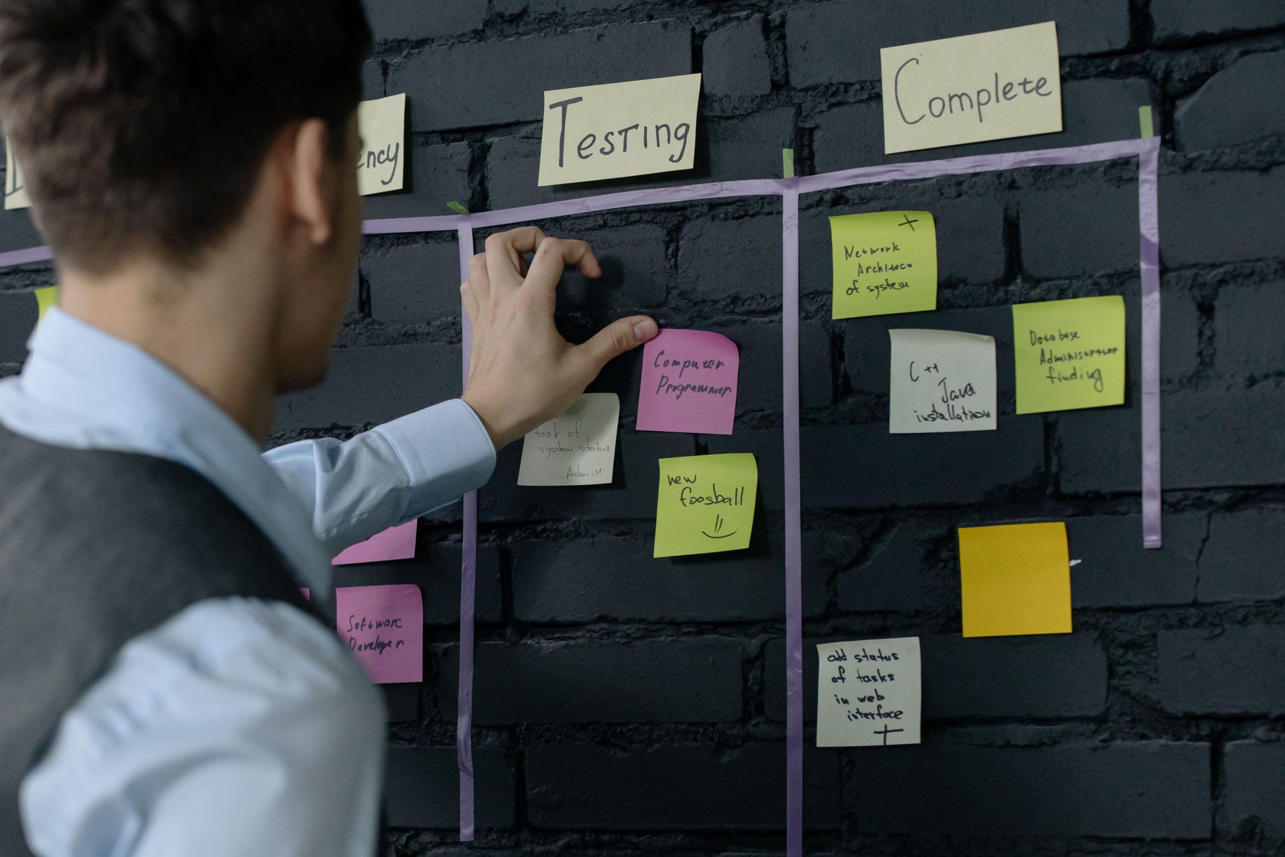 Homme organisant tâches avec notes adhésives murales