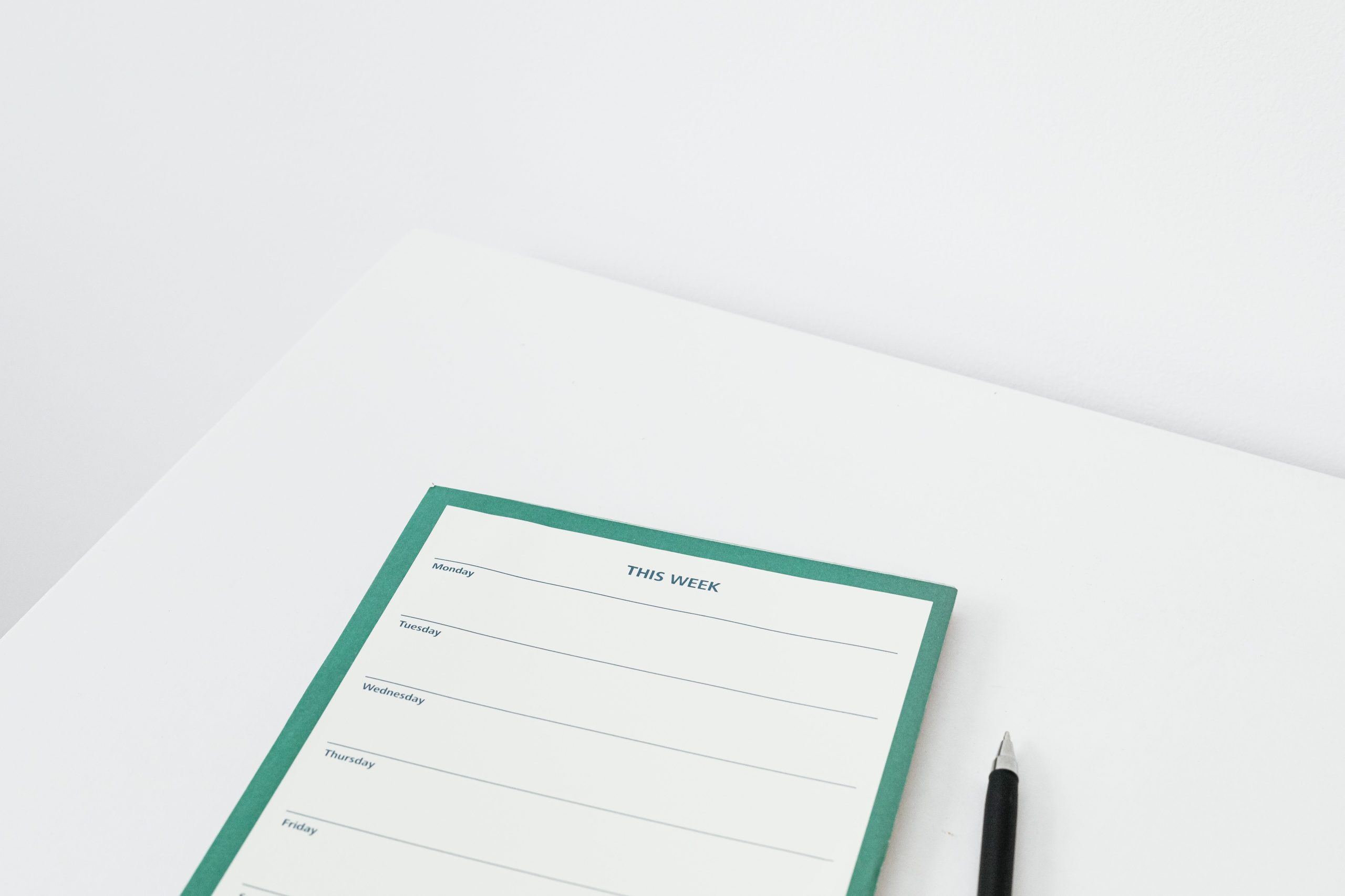 Planificateur hebdomadaire minimaliste avec stylo sur bureau blanc