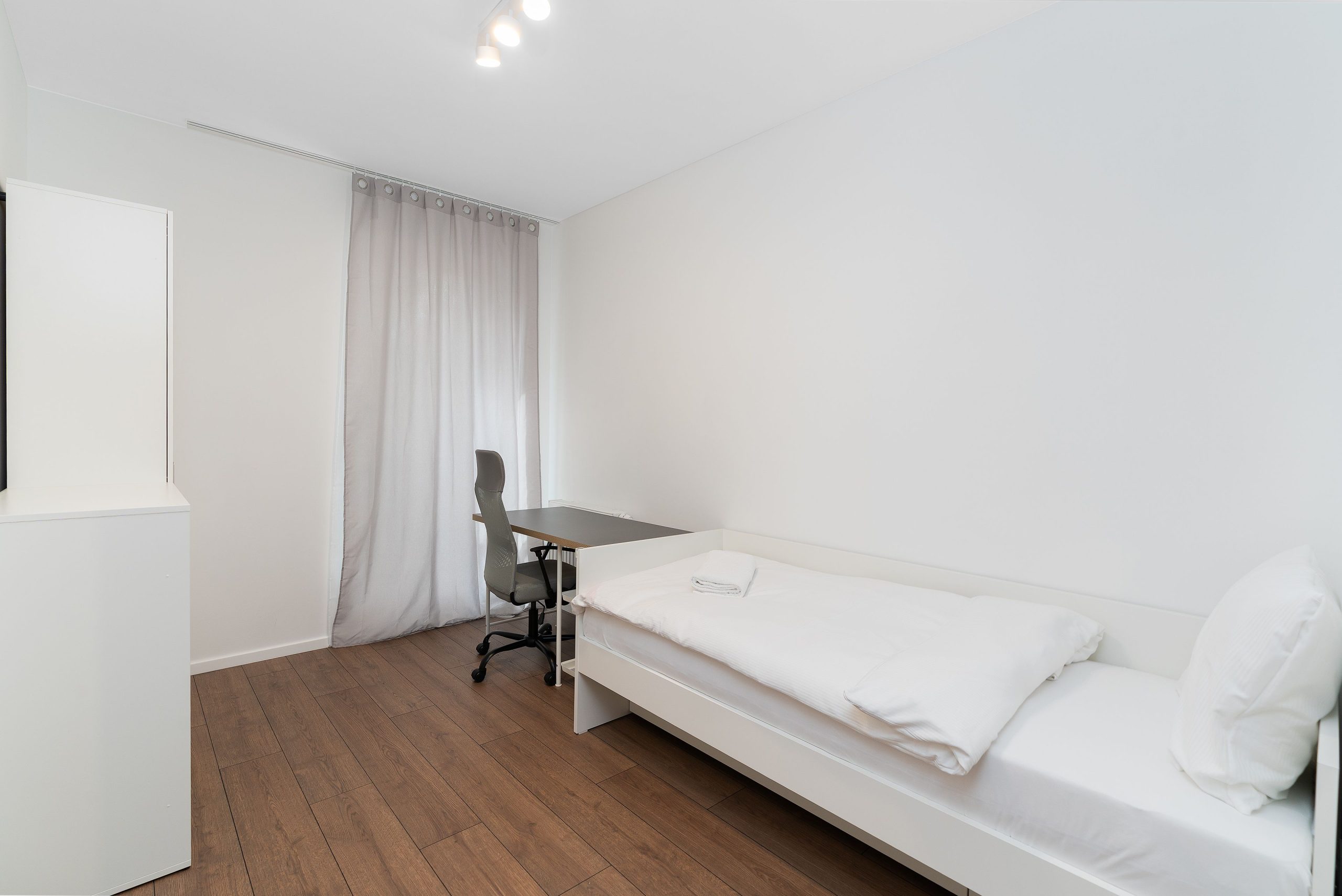 Chambre minimaliste lumineuse avec lit et bureau