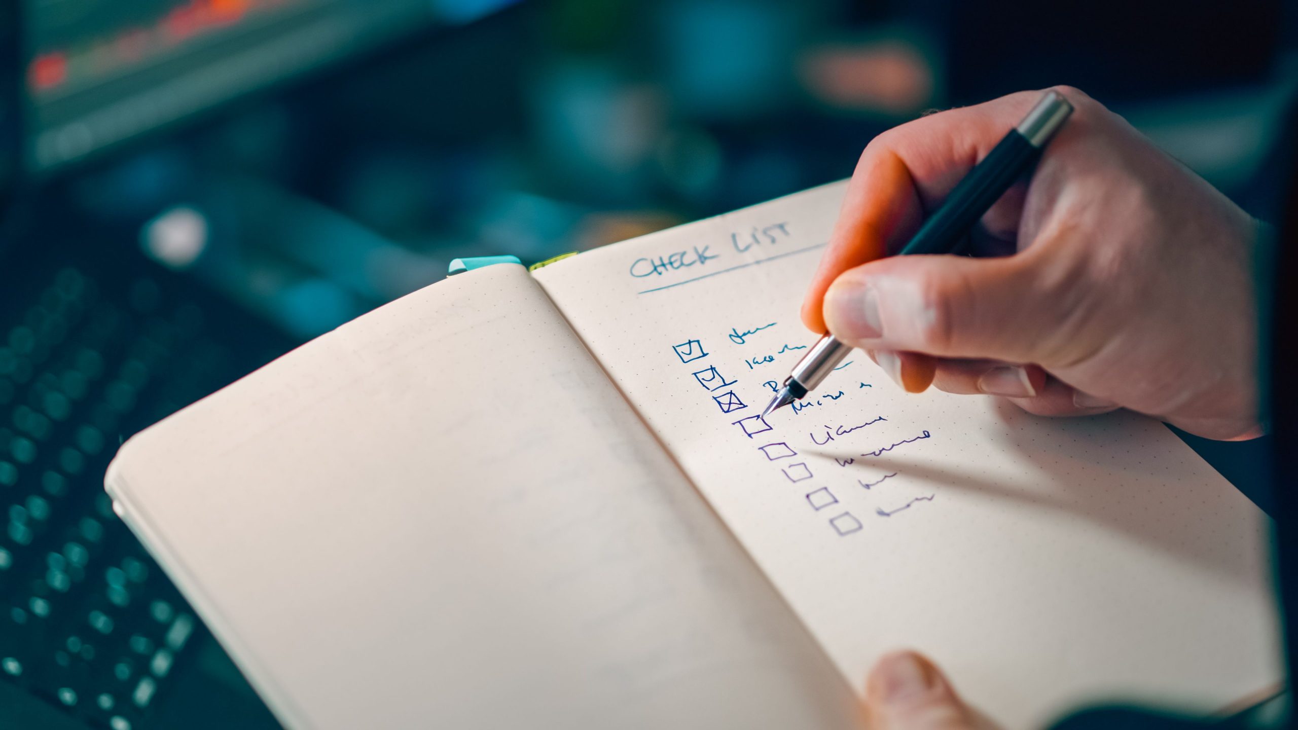 Main écrivant une liste de contrôle dans un carnet
