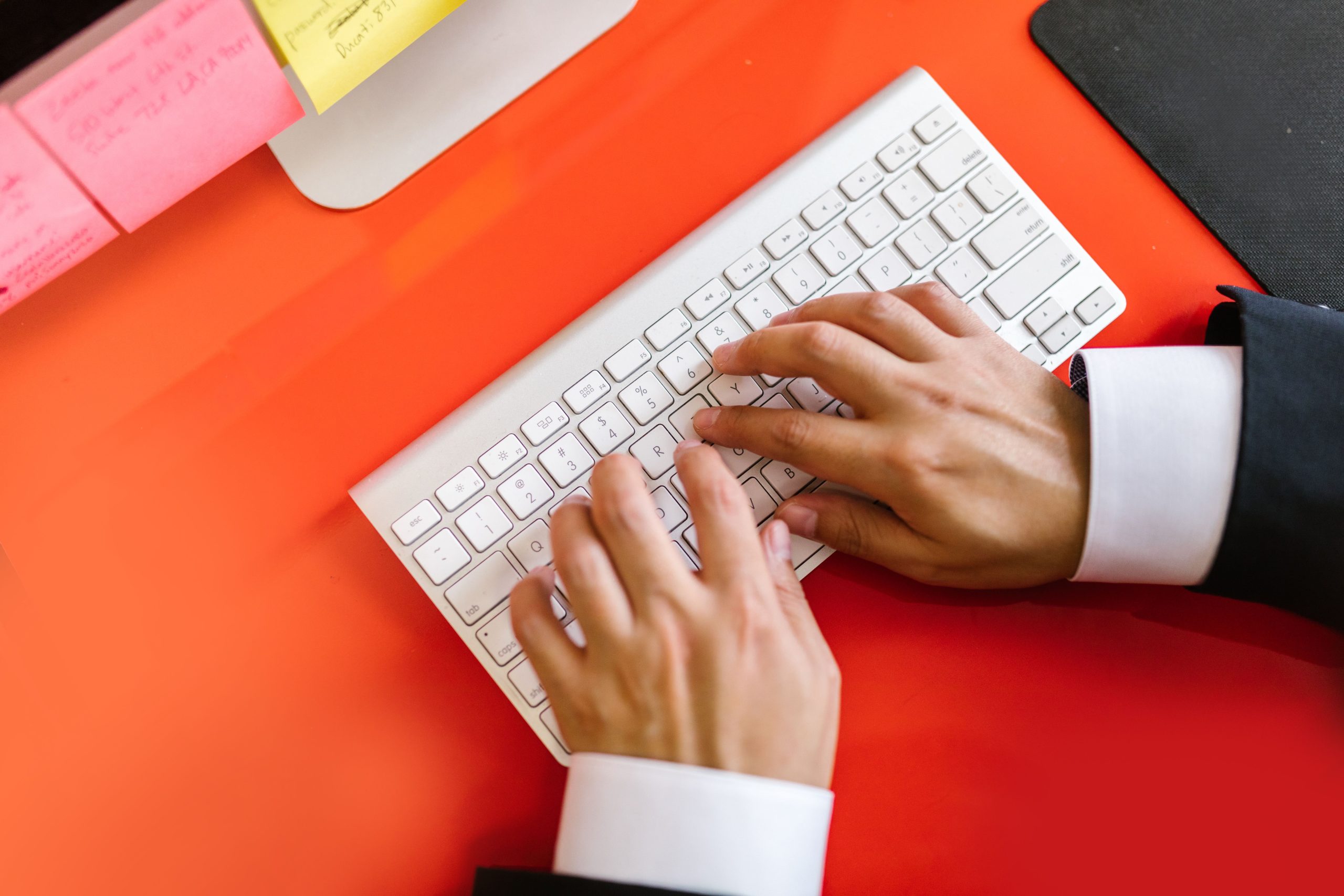 Mains tapant sur clavier wireless sur bureau orange