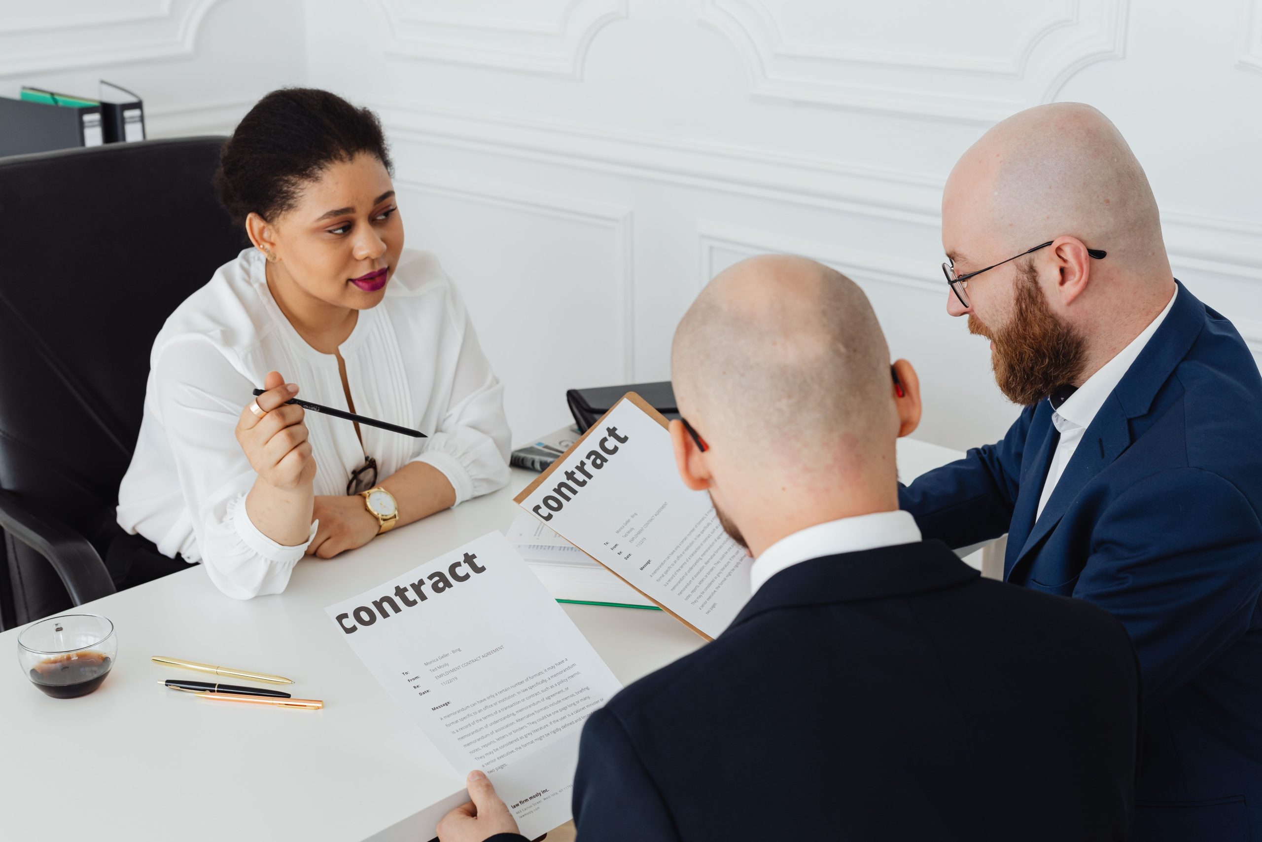 Trois professionnels discutent contrat bureau moderne