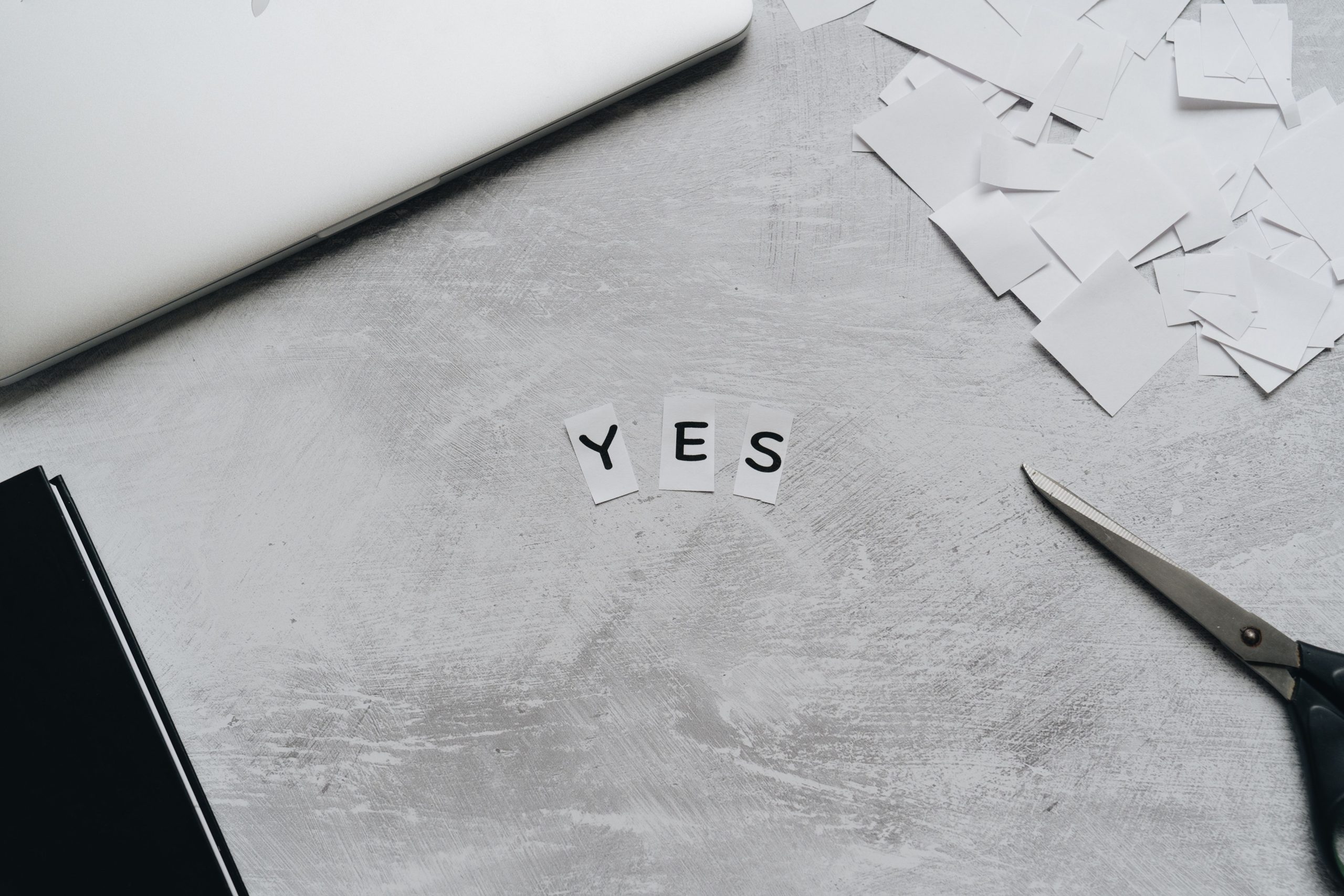 Découpes papier formant OUI avec ciseaux sur bureau