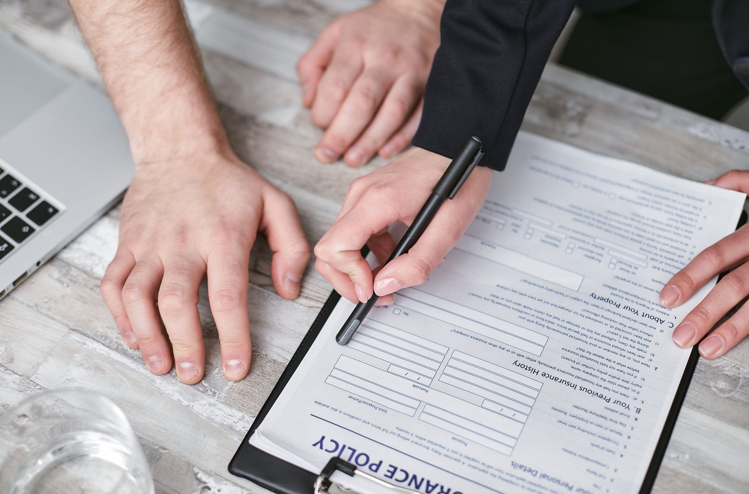 Deux personnes signent police assurance table bois